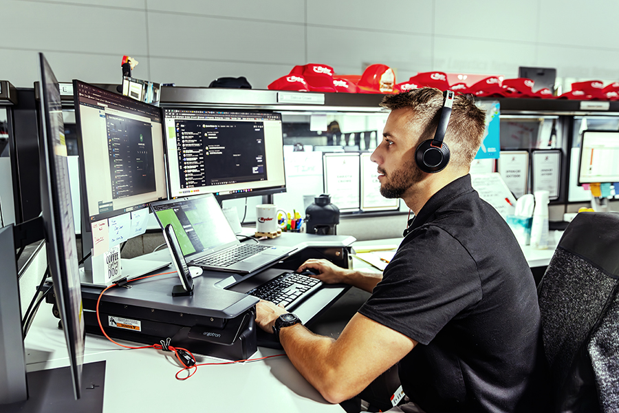 employee sitting at a desk typing on keyboard looking at multiple screens